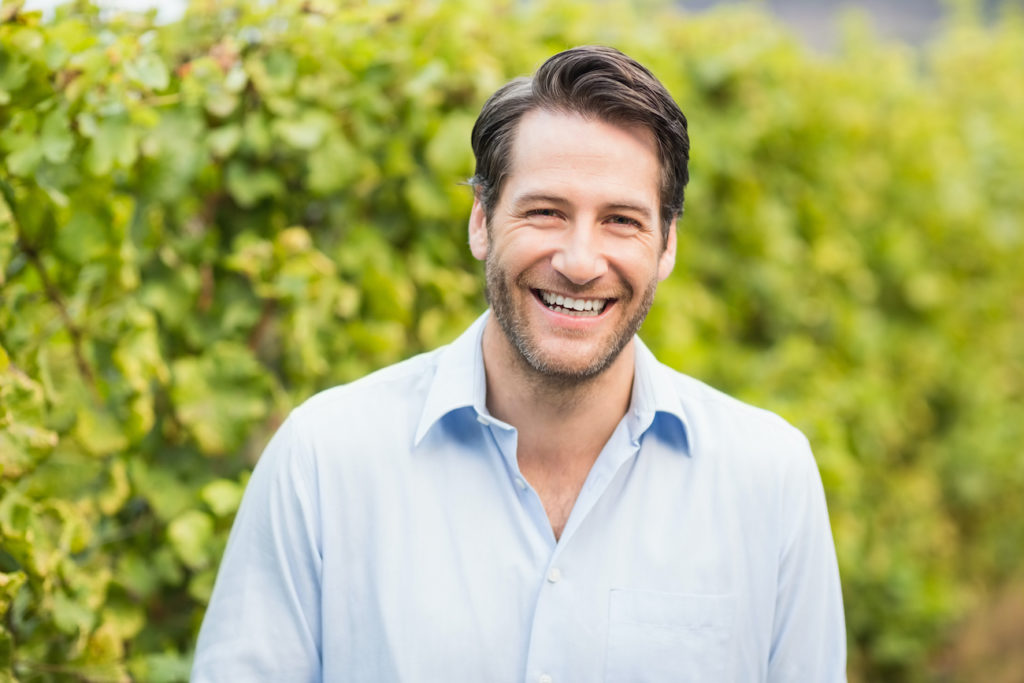 Young happy man smiling at camera in grape fields