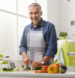 Happy Healthy Man cooking and cutting vegitables