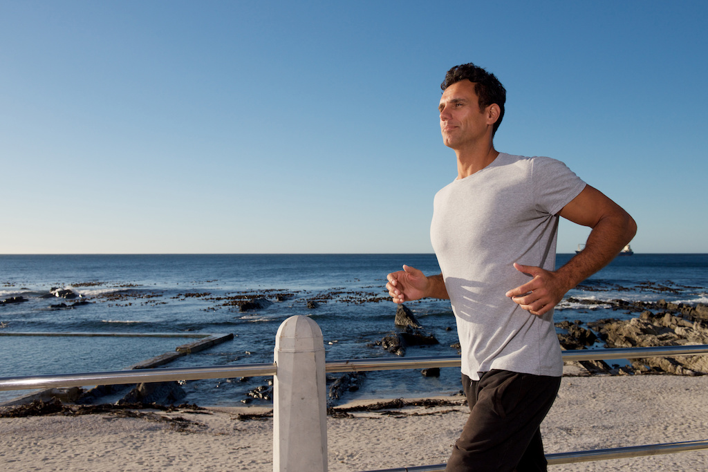 active middle age man running outside by sea