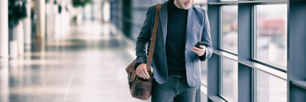 Business man texting on mobile phone in an airport